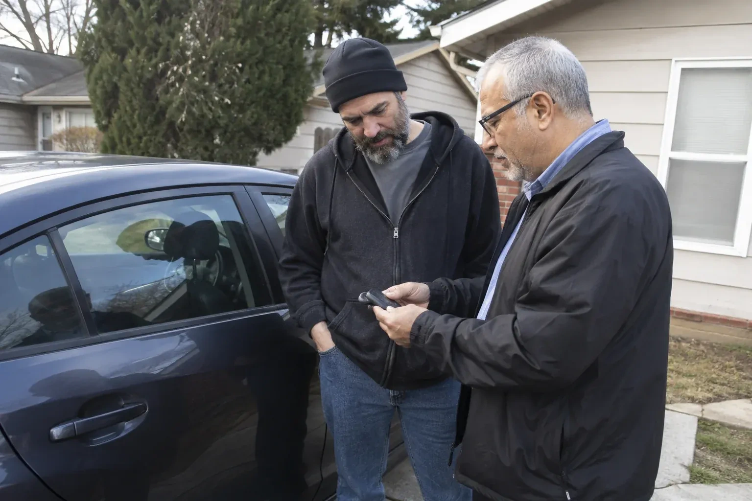 Two adults discussing a key fob beside a parked car. — Car Lockout Service, London